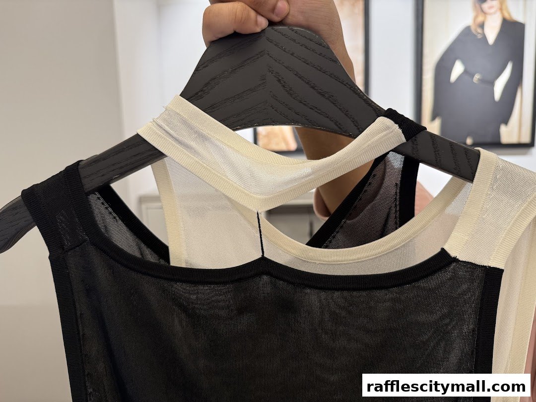 A close-up shot of two sleeveless tops with mesh detailing hanging on a hanger.