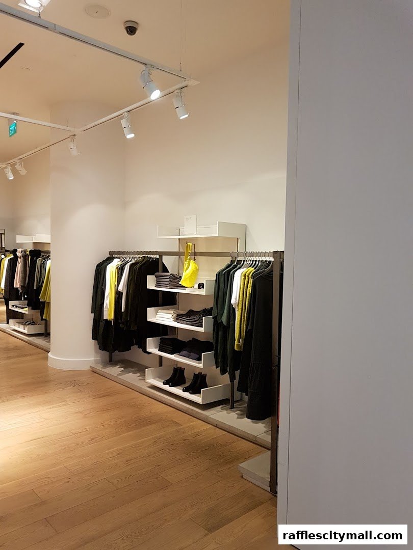 Interior view of a COS clothing store with racks of apparel and shelves displaying folded clothes and shoes.