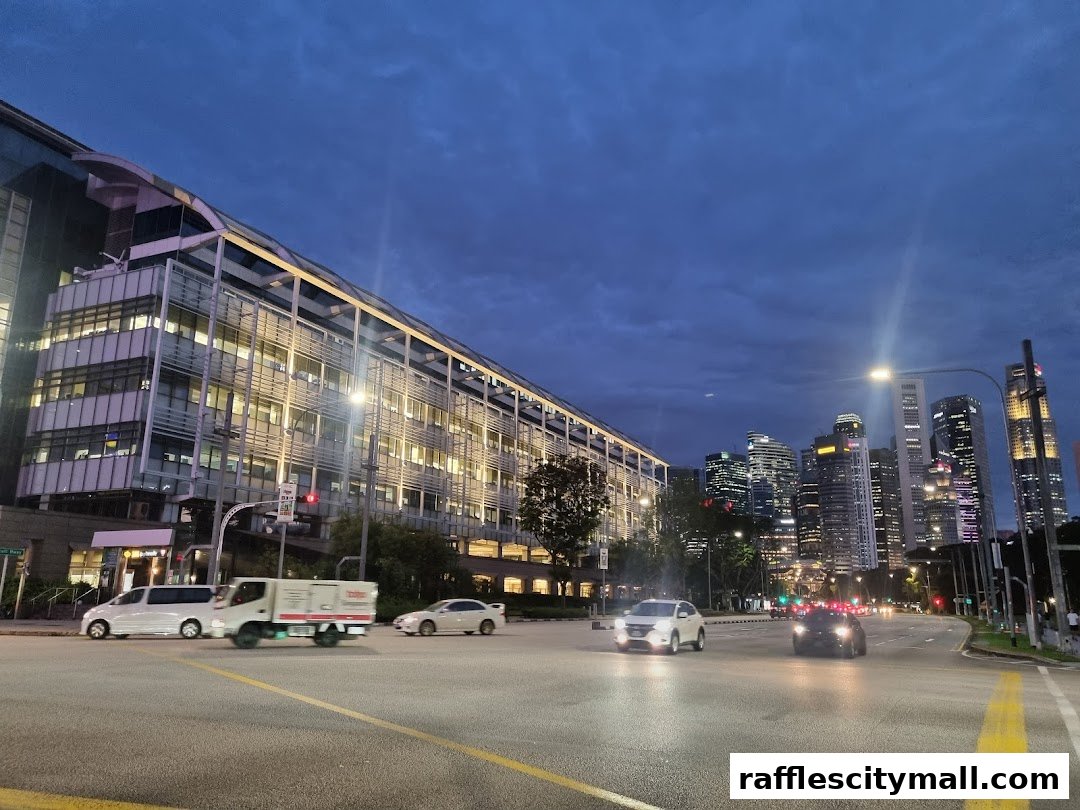 A city street at dusk with a modern building and skyscrapers in the background.