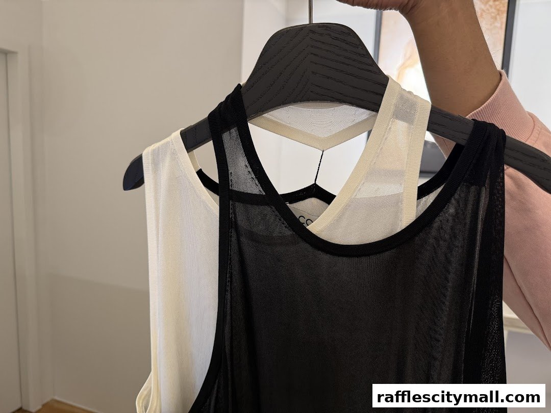 Close-up of two sleeveless tops, one black and one cream, on hangers.