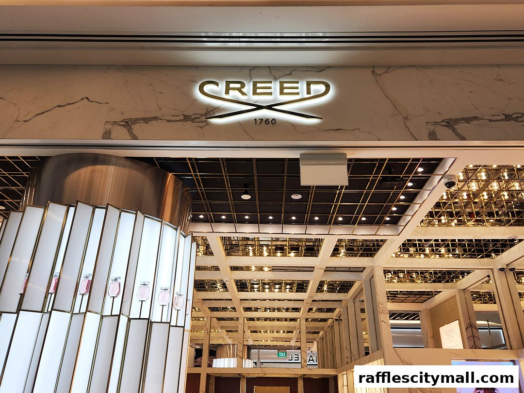 The elegant Creed store entrance with illuminated signage and perfume bottles displayed.