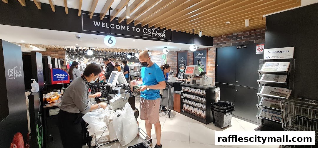 Customers at the checkout counters of CS Fresh supermarket, with staff assisting.