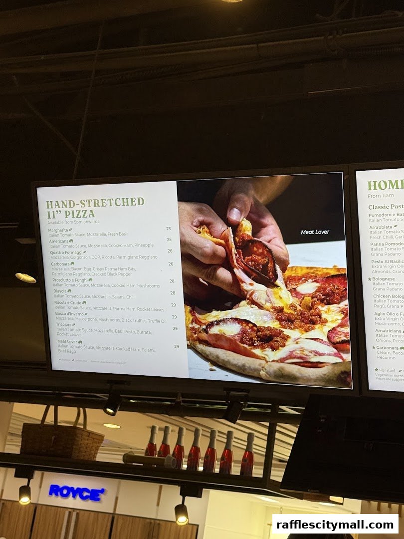 A digital menu board displaying hand-stretched pizzas and classic pasta dishes with prices.