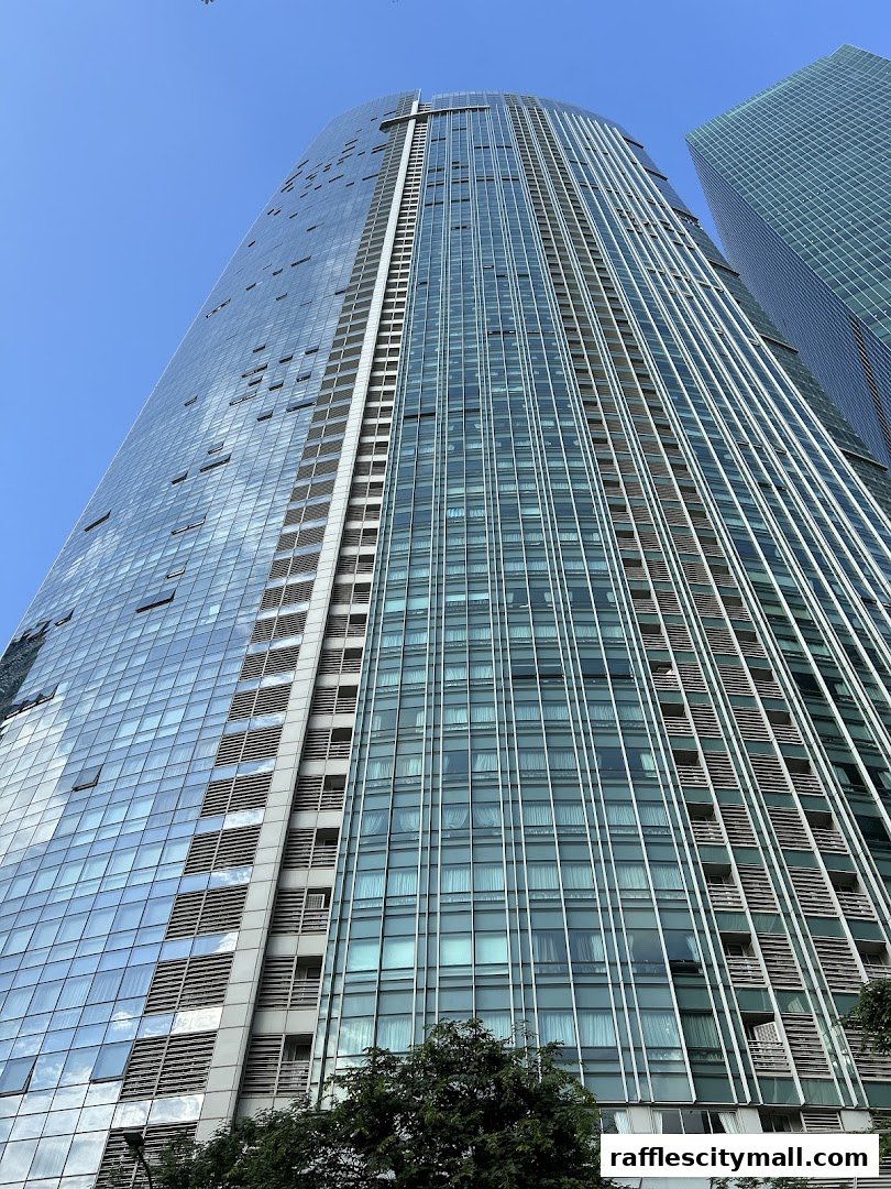 A low-angle shot of a modern skyscraper with a glass facade against a clear blue sky.