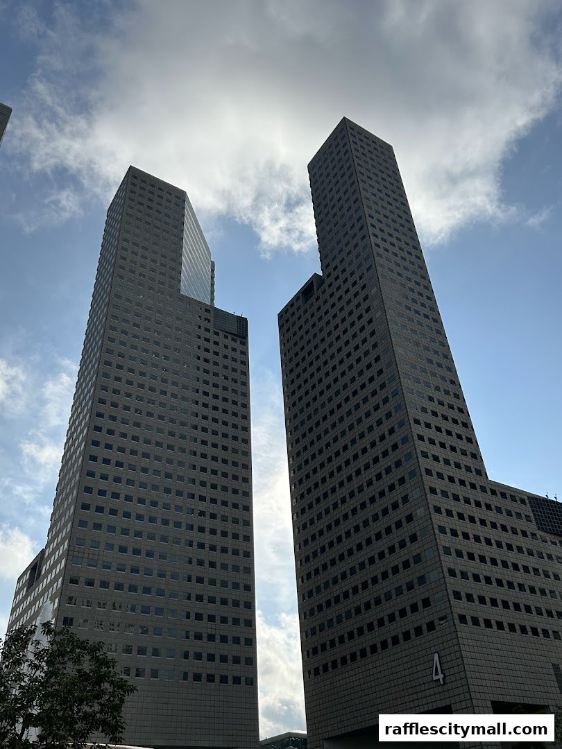 Two modern skyscrapers against a bright, cloudy sky.