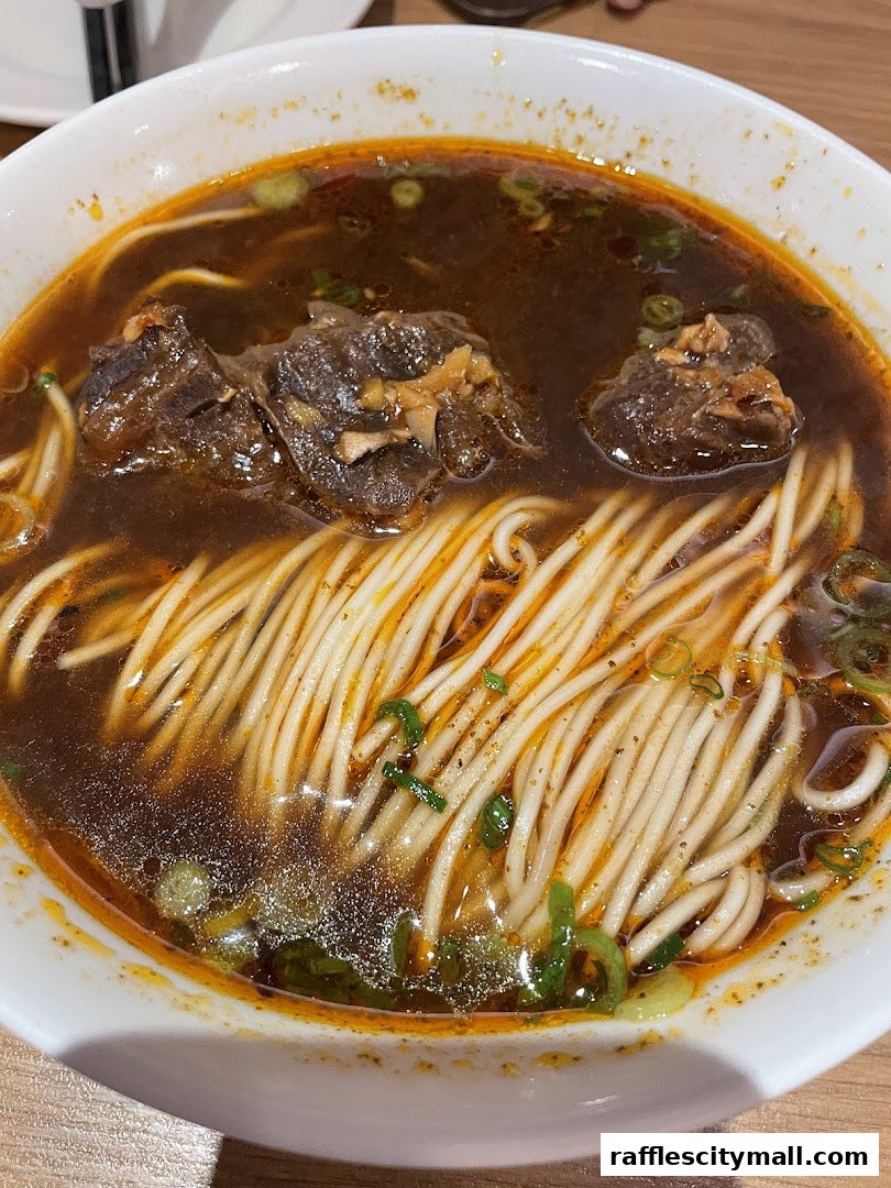 A close-up shot of a steaming bowl of beef noodle soup with tender beef chunks and noodles.
