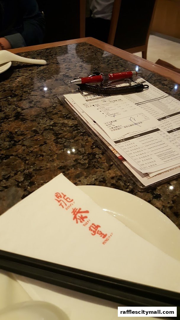 A table setting at Din Tai Fung with a menu, chopsticks, and a napkin.