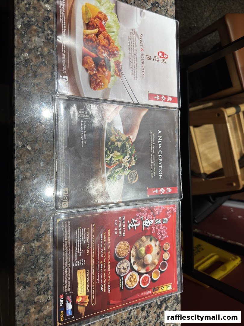 A close-up of a menu featuring popular dishes like Sweet & Sour Pork and Yu Sheng.