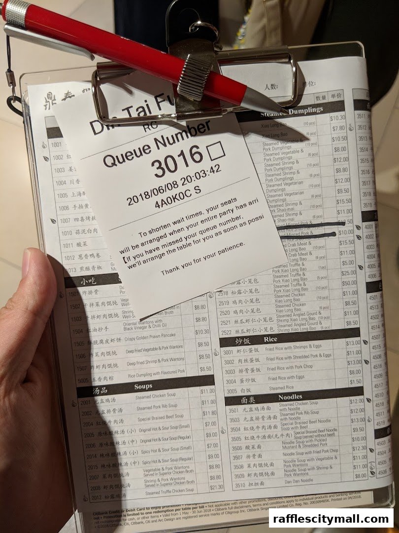 A person holds a queue number and menu from Din Tai Fung at Raffles City.