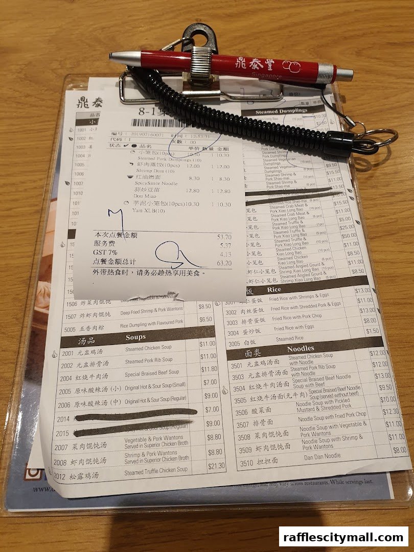 A close-up of a Din Tai Fung menu with various dumplings, soups, rice, and noodle dishes listed.