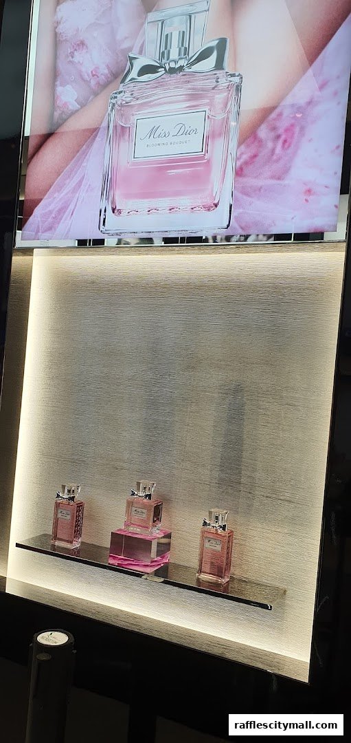 Dior Miss Dior Blooming Bouquet perfume bottles displayed on a shelf with a promotional image.