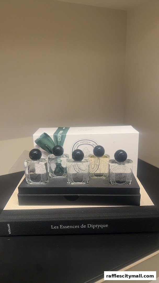 A set of Diptyque perfume miniatures displayed with a gift box and book.