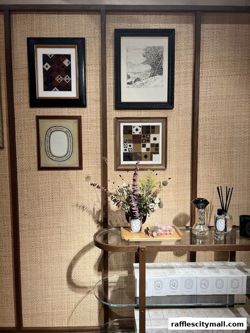 Diptyque Raffles City shop interior with framed art, floral arrangement, and boxed candles.