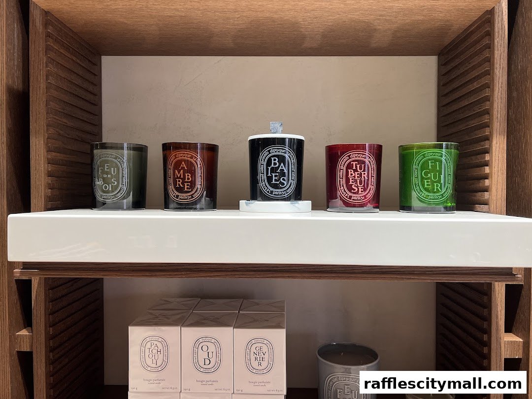 A display of Diptyque scented candles and boxed products on wooden shelves.