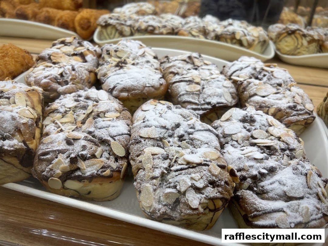 A close-up of freshly baked pastries topped with powdered sugar and sliced almonds.