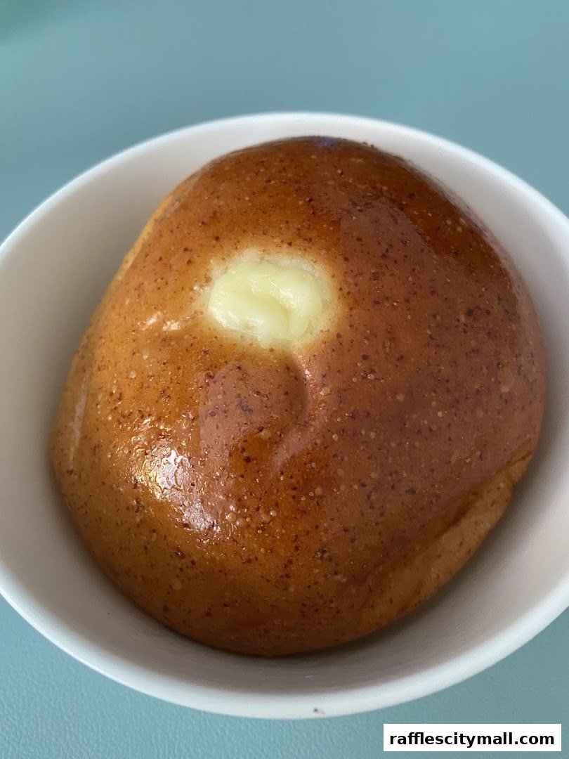 A close-up shot of a golden-brown pastry with a creamy filling in a white bowl.
