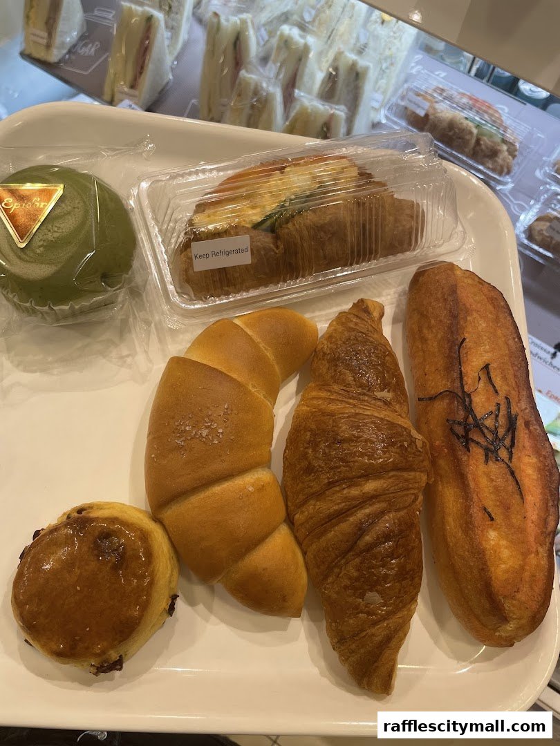 A tray of assorted baked goods including croissants, a bun, and a loaf of bread.