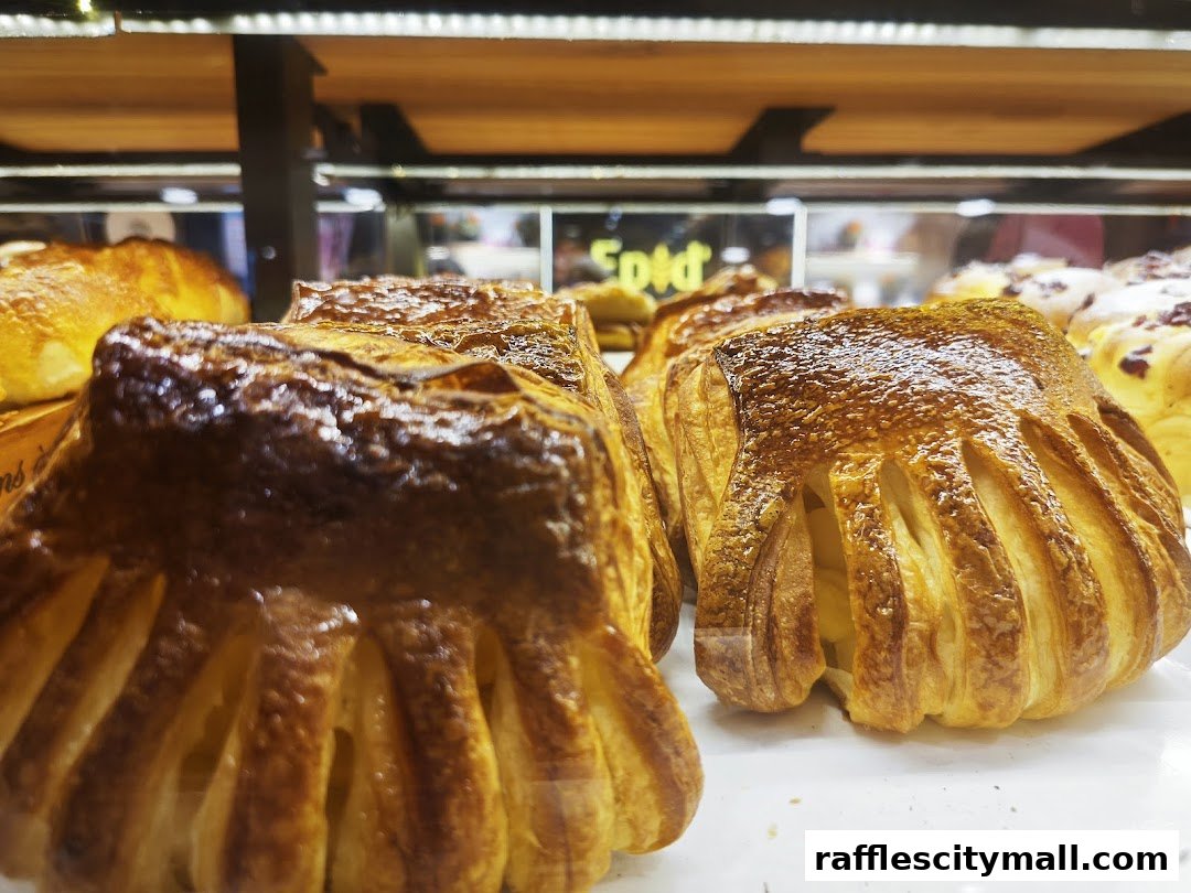 Close-up of golden-brown pastries with flaky layers displayed in a bakery case.