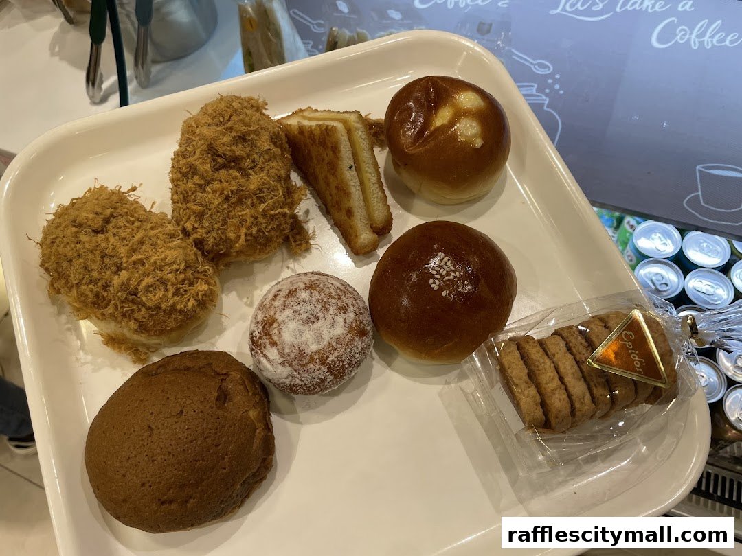 A tray of assorted baked goods including buns, a sandwich, and cookies.