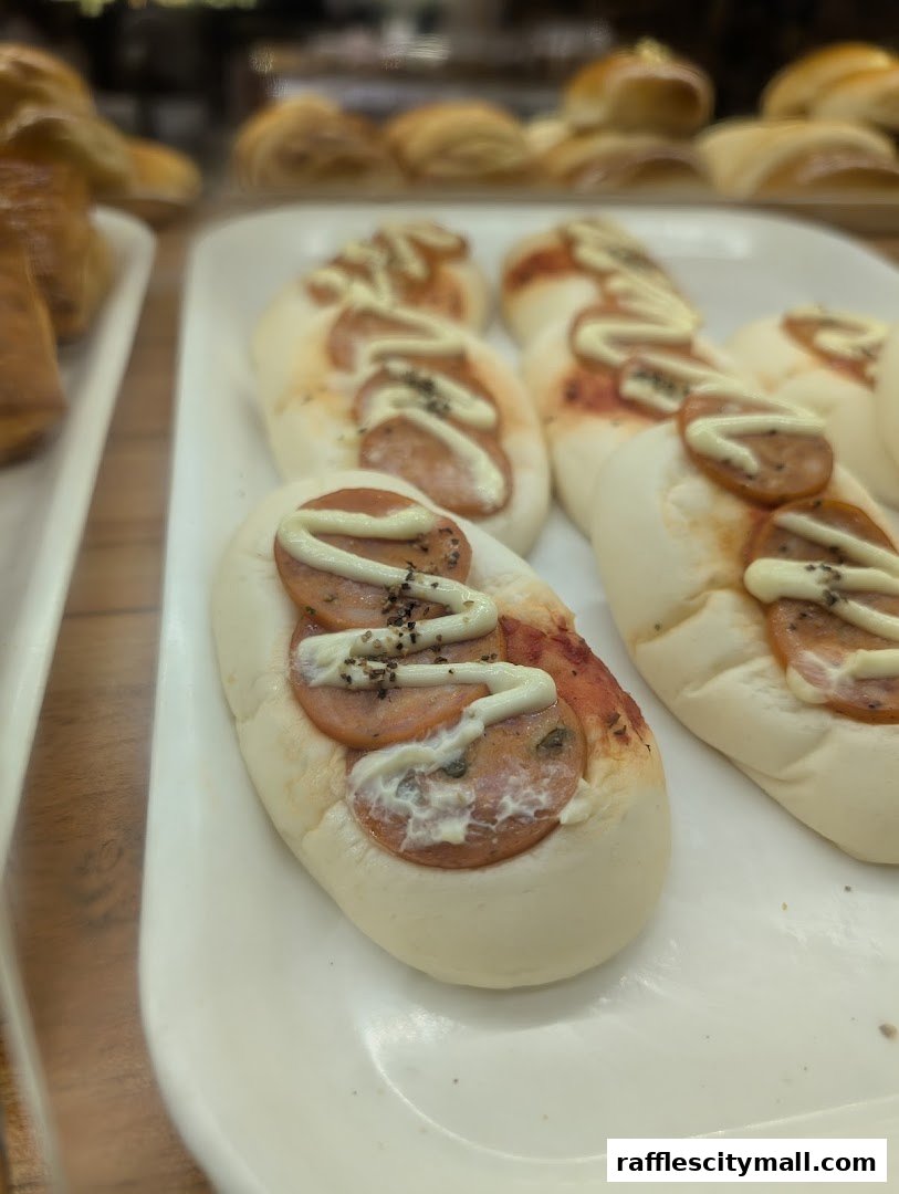 Close-up of savory bread rolls topped with sausage, sauce, and mayonnaise.