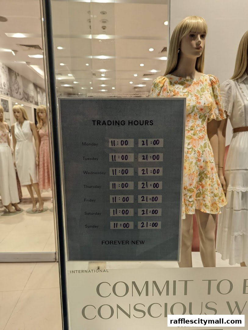 A sign displaying Forever New's trading hours is placed in front of mannequins wearing dresses.