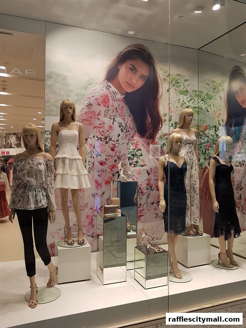 Mannequins display fashionable dresses and accessories in a brightly lit shop window.