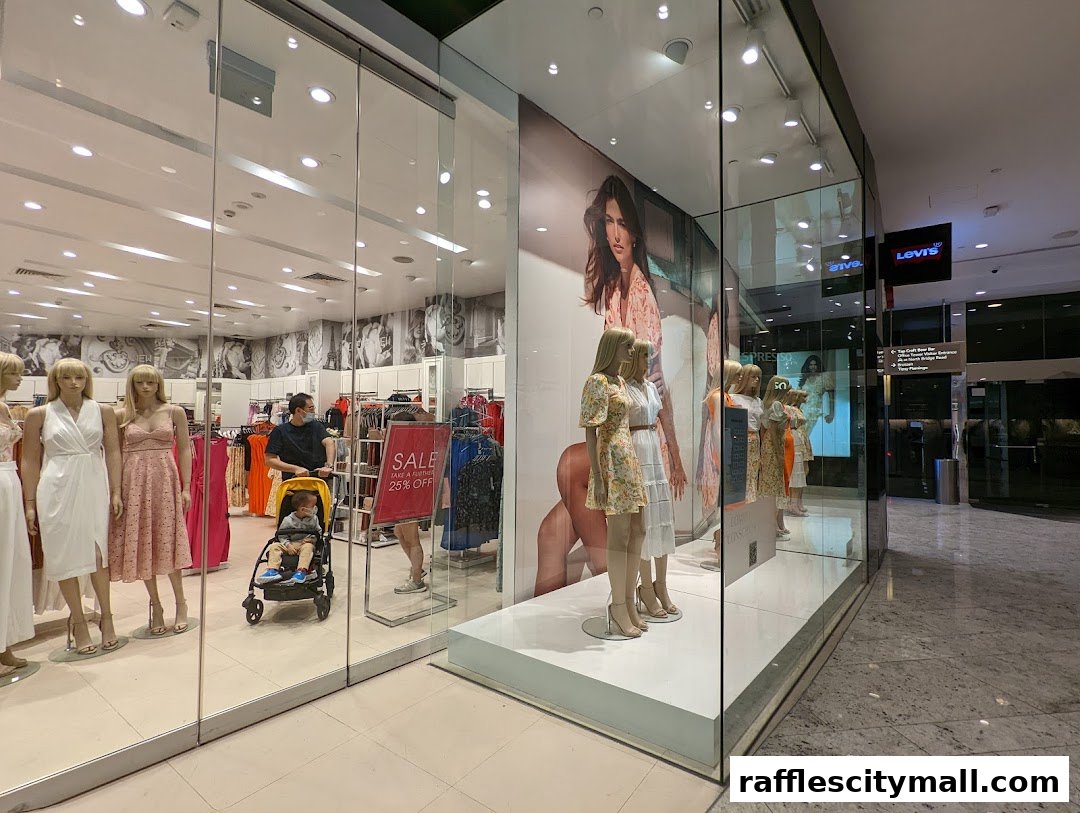 Shop window display featuring mannequins in dresses and a sale sign.