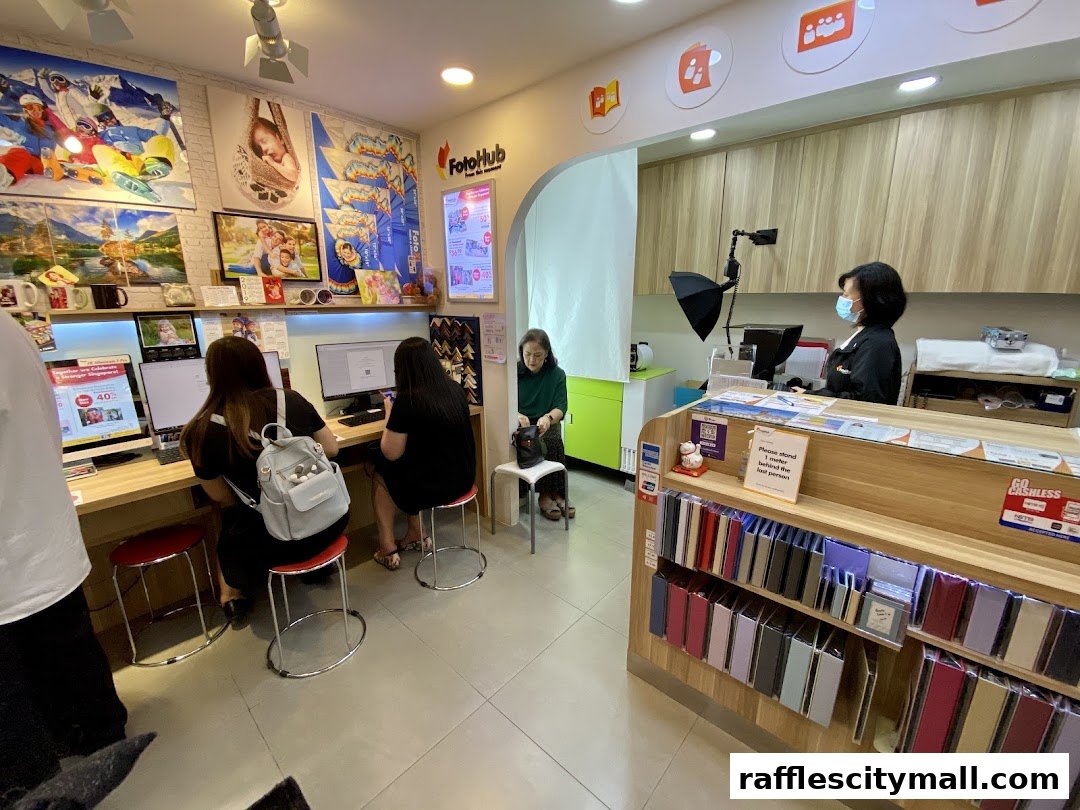 Customers are served at FotoHub Raffles City, with staff assisting at computers and a photo booth setup.