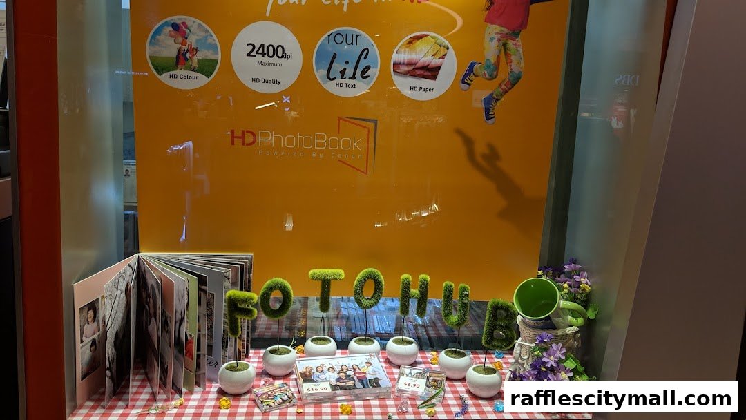 A shop window display featuring a photobook, grass letters spelling 'FOTOHUB', and decorative plants.