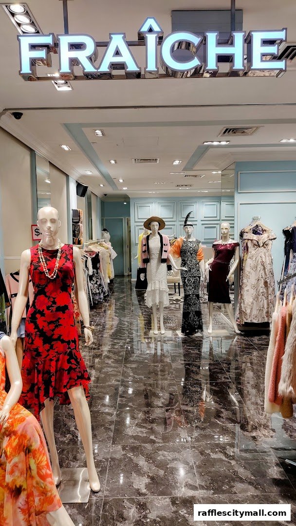Mannequins dressed in elegant fashion are displayed inside a well-lit clothing store.
