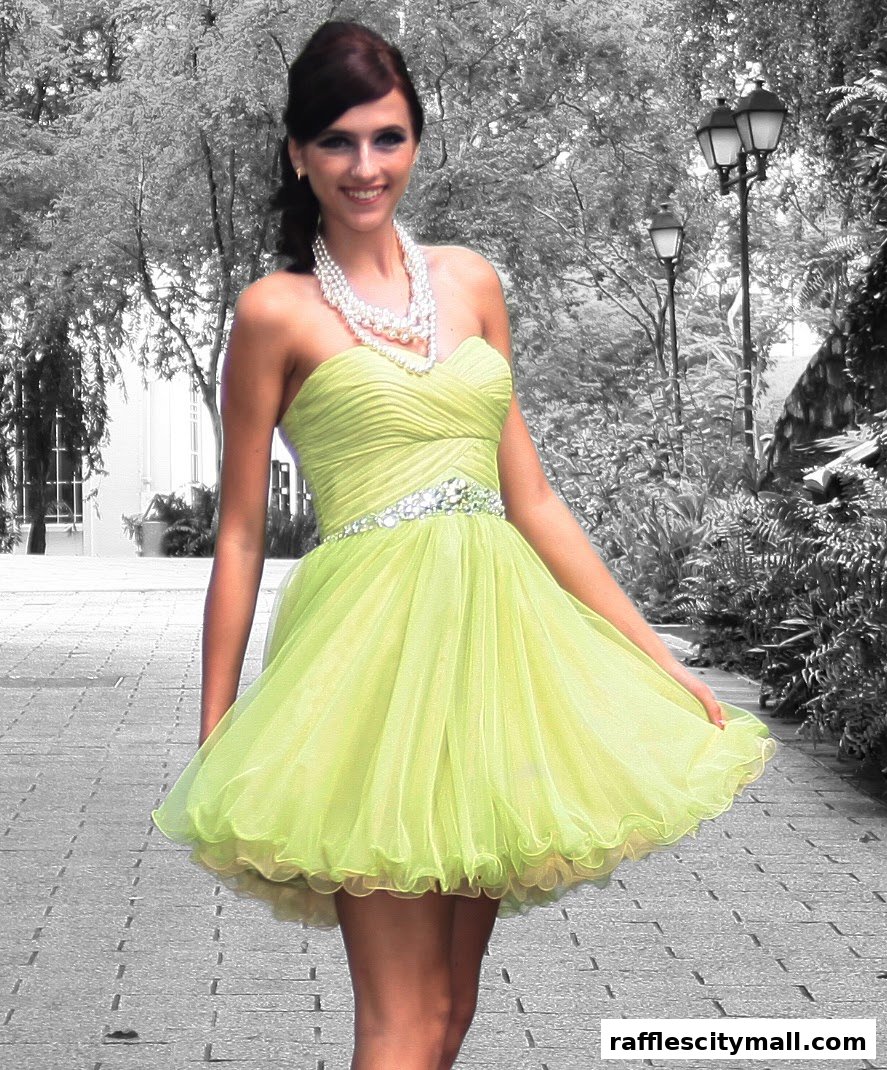 A smiling woman in a lime green strapless dress with a pearl necklace.