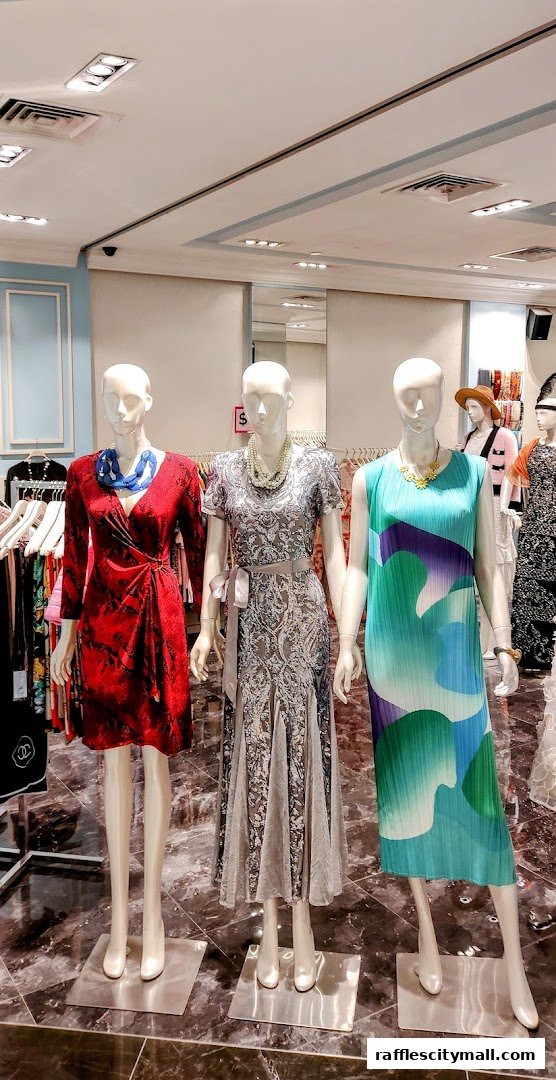 Mannequins display elegant dresses in a well-lit retail store.