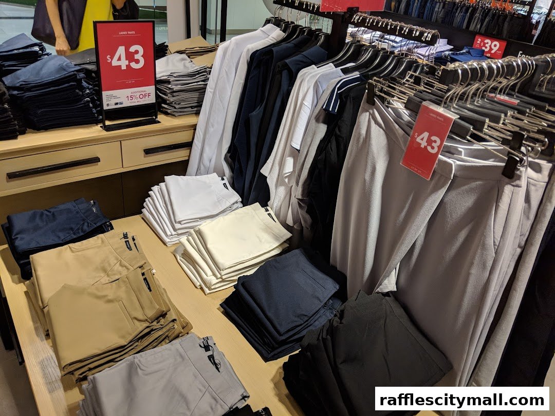 A display of folded and hanging pants in various colors, with a sale sign.