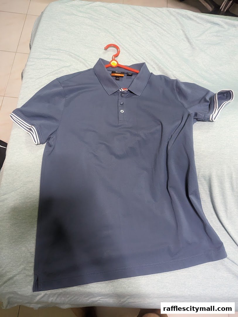 A dark blue polo shirt with white striped cuffs hangs on a red hanger.
