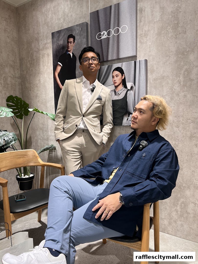 Two men posing in a G2000 store with fashion posters on the wall.