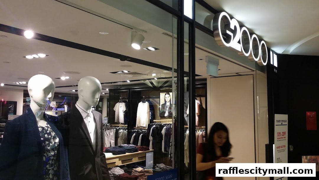 G2000 store window display featuring mannequins and clothing, with a shopper passing by.
