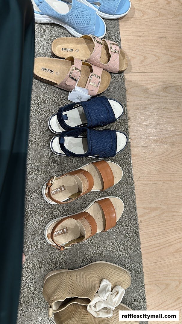 A selection of Geox sandals and shoes displayed on a rug and wooden floor.
