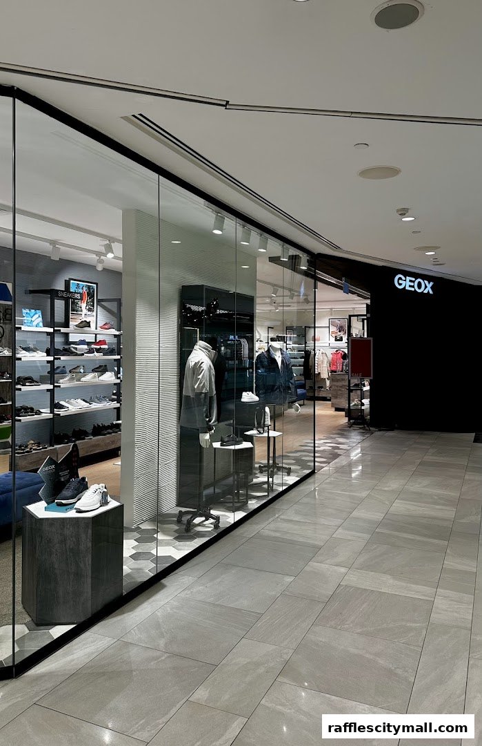 The Geox Raffles City store features a modern glass facade displaying shoes and mannequins.