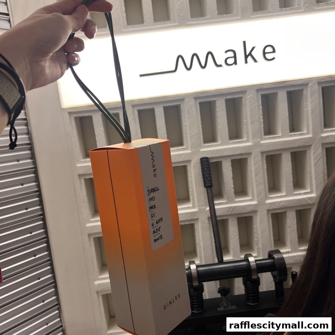 A hand holds an orange and white box with text labels, in front of a white textured wall.