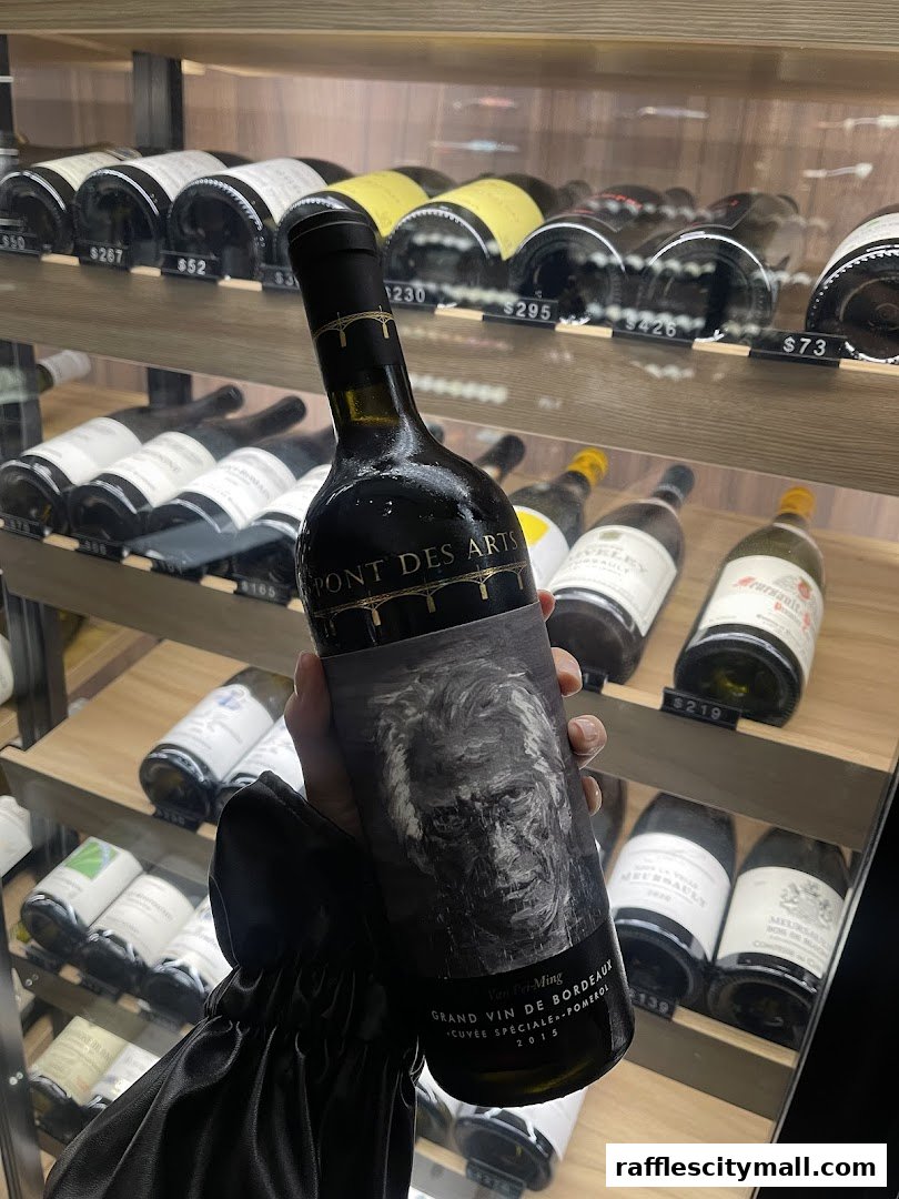 A hand holds a bottle of Grand Cru wine in front of a display of wine bottles.