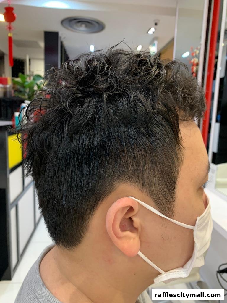 A close-up side profile of a person's head with styled curly hair and a face mask.