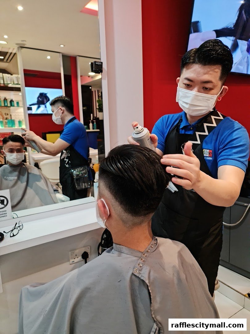 A hairstylist sprays hairspray on a client's hair in a modern salon.