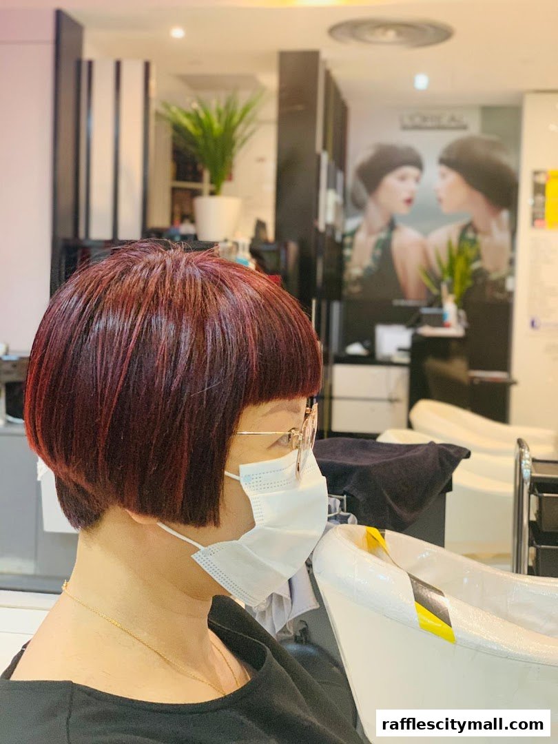 A person with a stylish bob haircut wearing a mask in a salon.