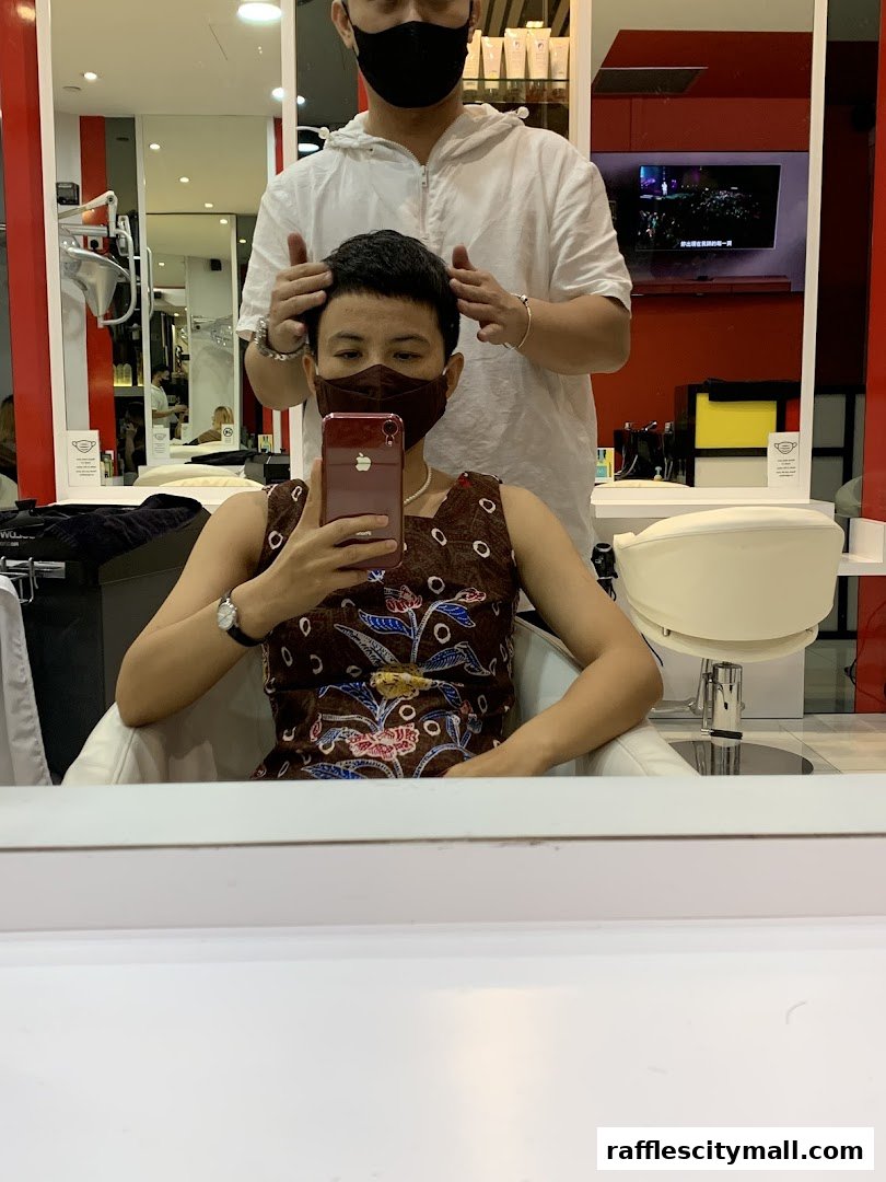 A person in a salon chair is getting their hair styled by a stylist.