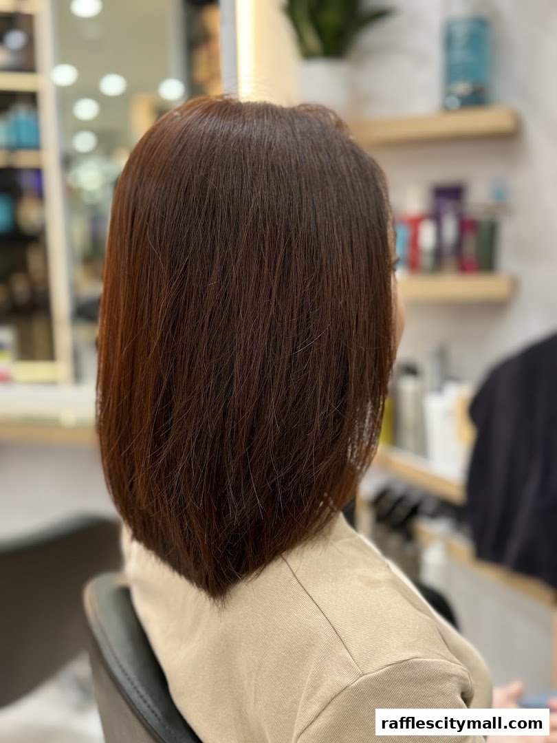 A person with freshly styled, dark brown, shoulder-length hair sits in a salon chair.