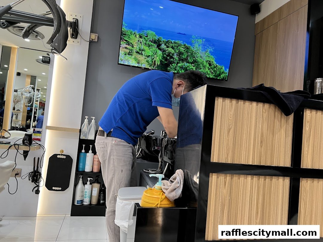 A barber in a blue shirt and mask works at a sink in a modern salon.