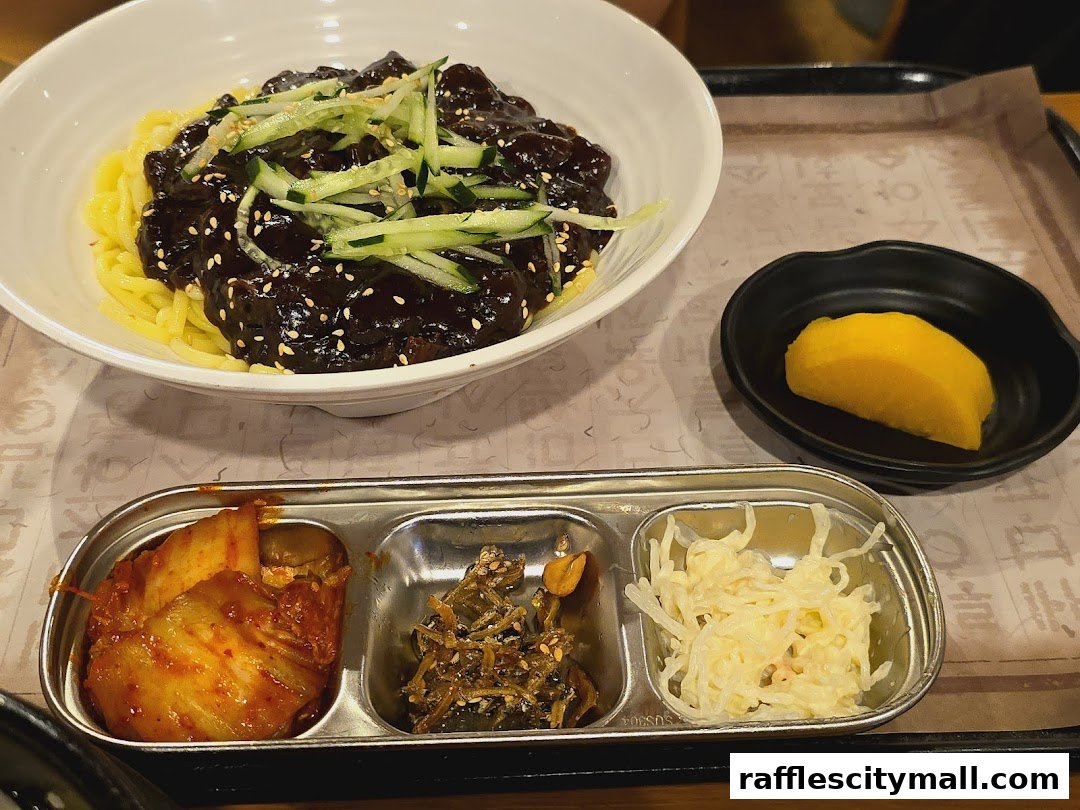 A bowl of Jajangmyeon with side dishes including kimchi and pickled radish.