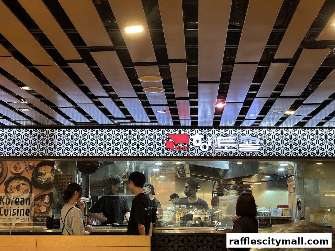 People ordering at a Korean restaurant counter with a view of the kitchen.