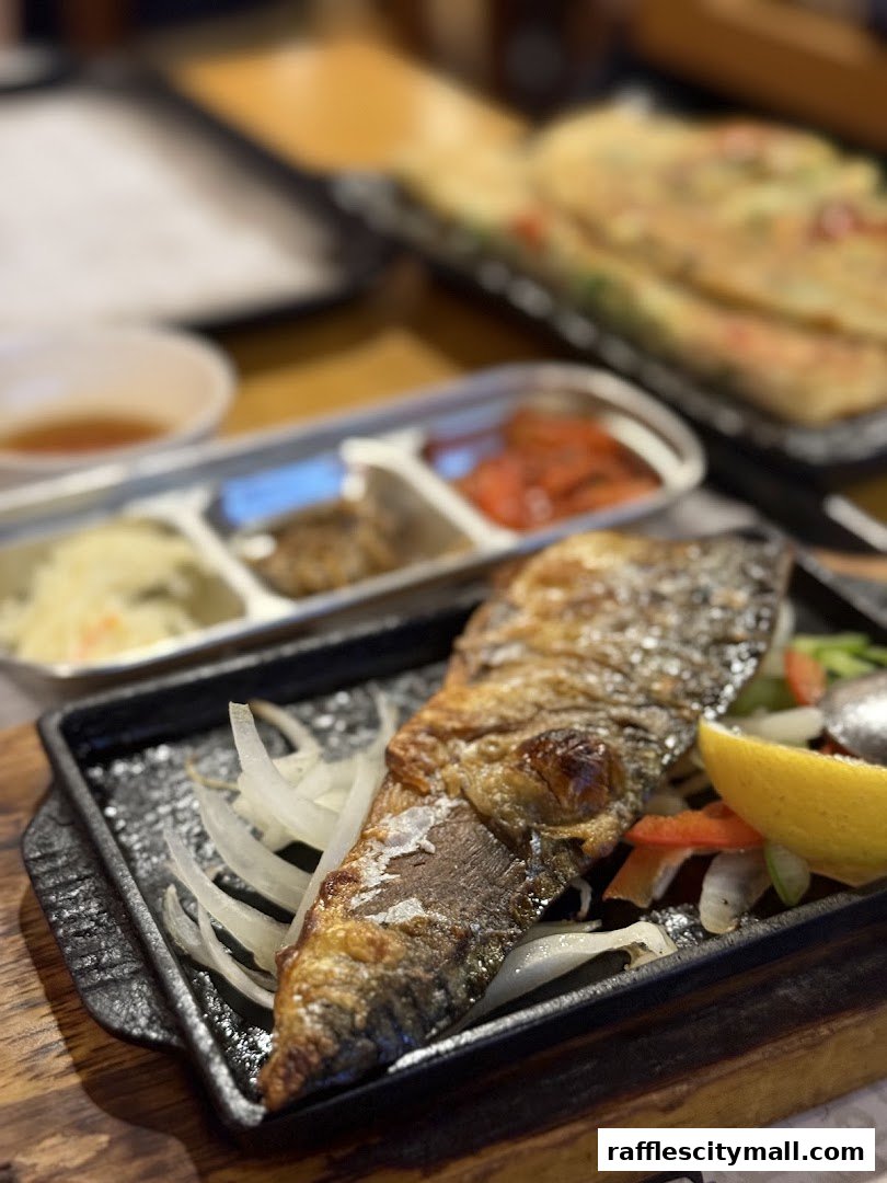 A close-up of a grilled fish dish with side dishes and a lemon wedge.