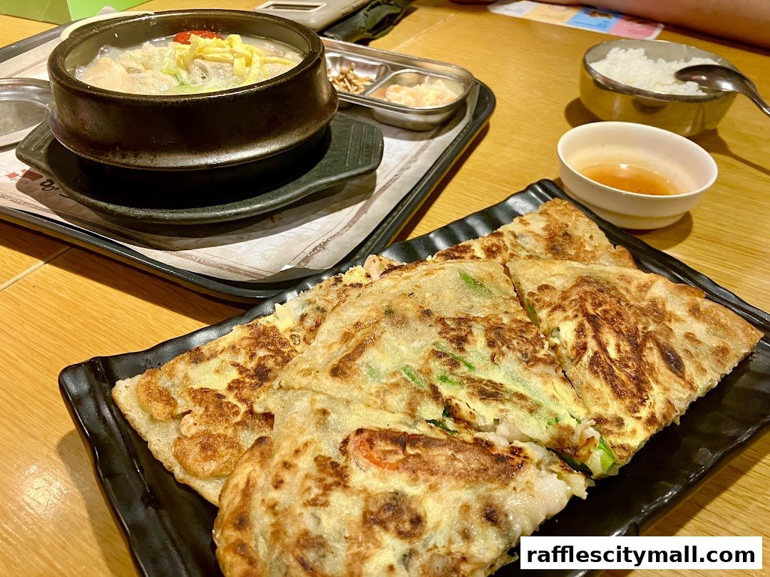 A close-up of Korean dishes including a savory pancake and a hearty soup with rice.